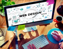 Business website design and development displayed on a computer screen with web graphics and programming concepts.