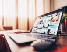 Laptop displaying a business website on a wooden desk in a modern workspace.